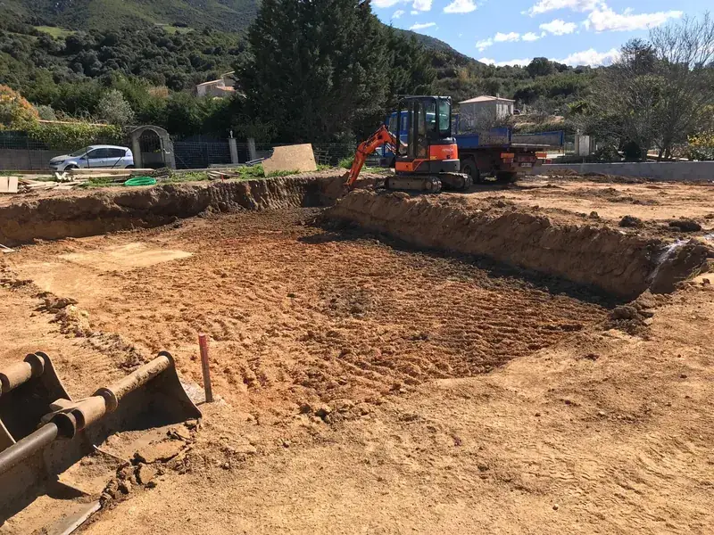 Plateforme de terrain décaissée et nivelée à la mini-pelle, collines corses en arrière-plan